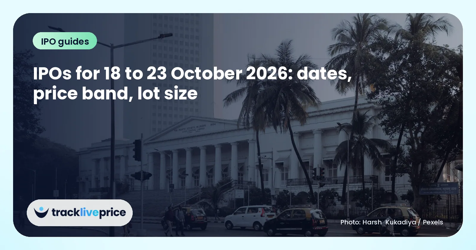 Colonnaded heritage building beside a busy road with palm trees and a tall office tower behind it in Mumbai